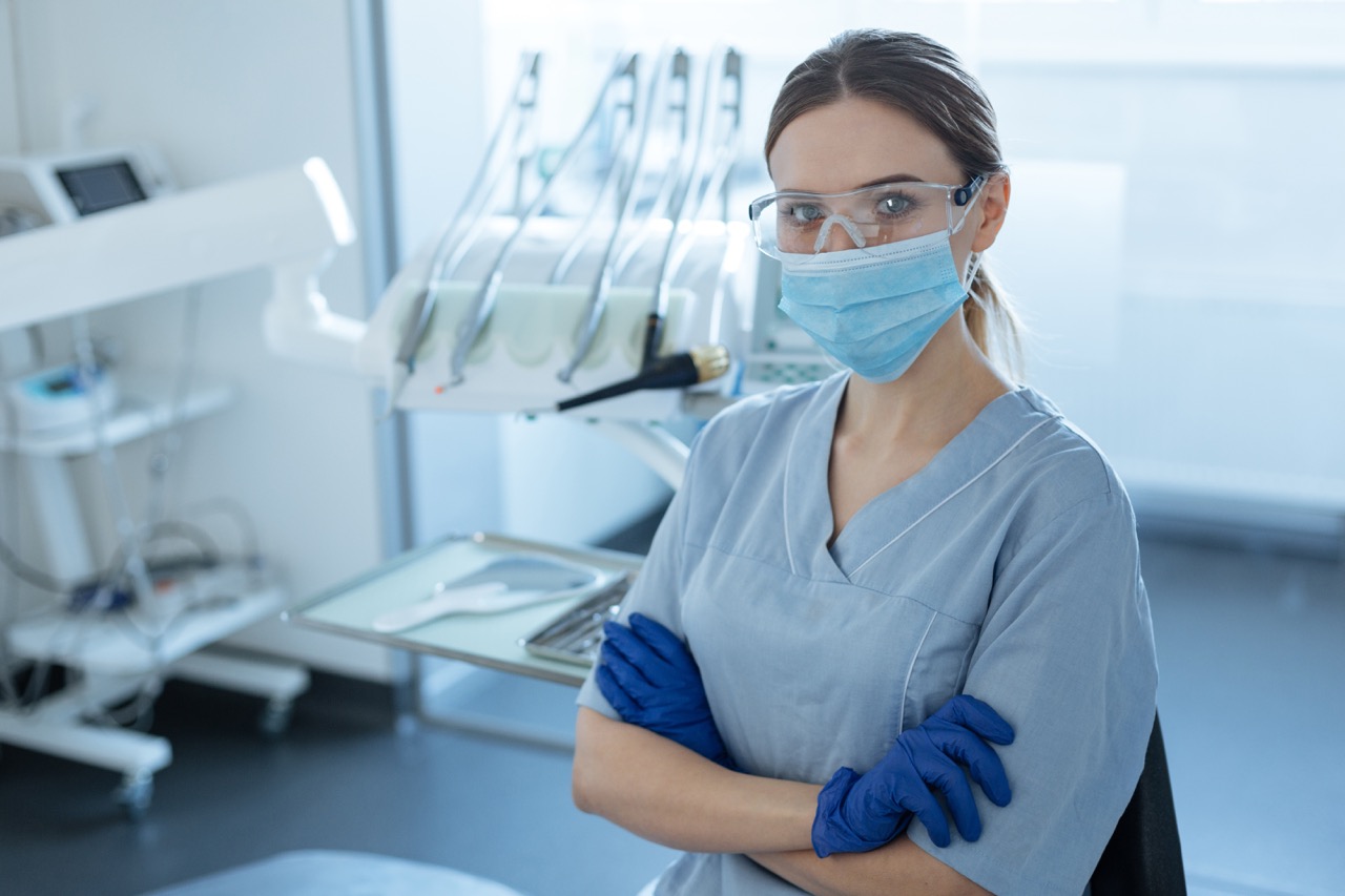 A dental hygienist in safety goggles and a mask
